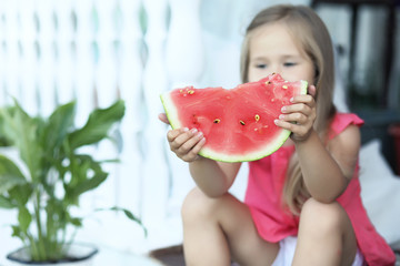 Young girl on the porch of the house eating sweet watermelon