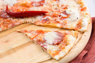 Hot sliced classic pepperoni pizza on wooden board, close up. Fresh pizza with pepperoni, mozzarella and tomato sauce, copy space. Italian traditional cuisine, food
