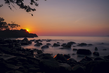 Un magnifique couché de soleil  sur une plage rocailleuse en Thaïlande 