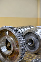 Gear wheel, gear after machining on lathe and CNC milling machine lies on a wooden rack in the shop.