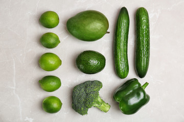Different green vegetables and fruits on grey background, top view