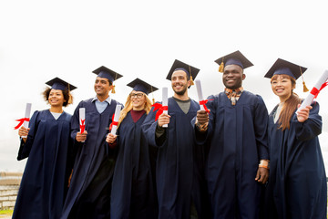 happy students in mortar boards with diplomas