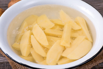 Sliced potatoes in water in a metal bowl