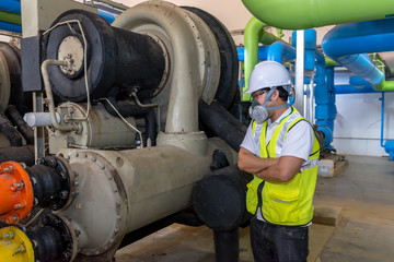 Asian engineer wearing glasses working in the boiler room,maintenance checking technical data of heating system equipment,Thailand people Wearing a gas mask