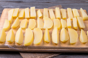 Frozen potatoes on a cutting board on a wooden table