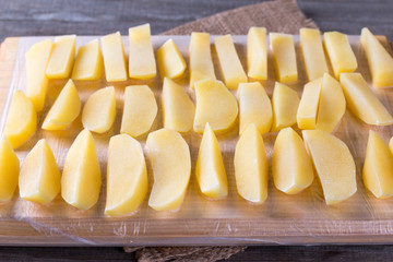 Frozen potatoes on a cutting board on a wooden table