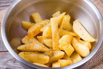 Raw slices of potatoes in a bowl with herbs