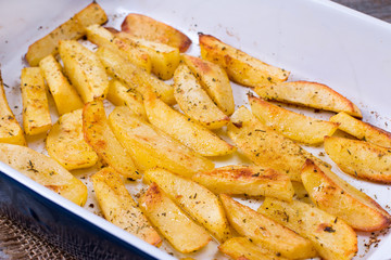 Homemade baked potatoes with spices in a form.