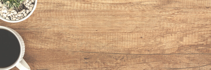 Panoramic top view on a wooden empty desk with coffee cup and cactus