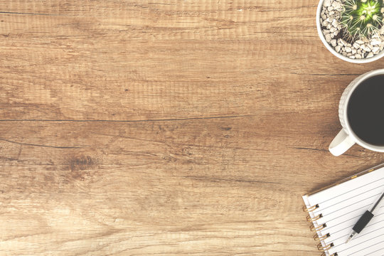 Top view on a wooden empty desk with open notebook, coffee cup and cactus