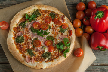 Traditional Italian pizza with tomatoes cheese and pesto on the boards