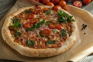 Traditional Italian pizza with tomatoes cheese and pesto on the boards