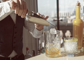Barman is adding ice to a cocktail, toned