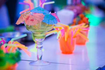 Colorful margarita cocktail isolated. Party time concept. Summer tropical cocktails. Barman´s table with straws, umbrellas and cocktails. Bokeh background.