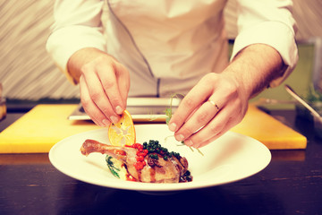 Chef is decorating a dish with dried orange and pea sprout, toned