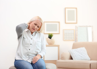 Mature woman suffering from neck pain at home