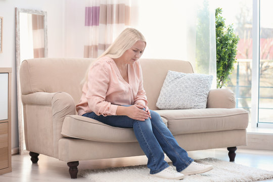 Mature Woman Suffering From Knee Pain At Home