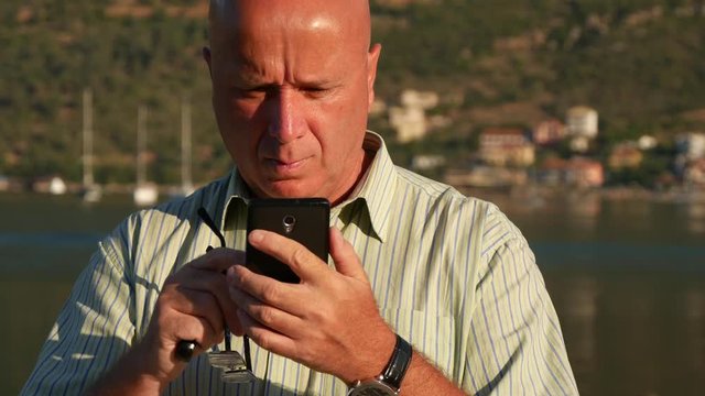 Businessperson in Harbor with Eyeglasses in Hand Look in Cellphone Email Box