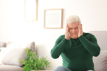 Mature man suffering from headache at home