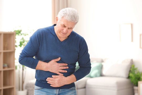 Mature man suffering from stomach ache at home