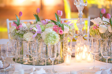 Luxury table settings for fine dining with flowers, candles and glassware, beautiful blurred background.