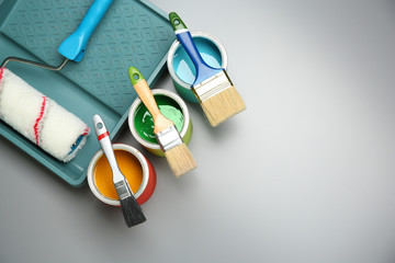 Paint cans, brushes, roller and tray on grey background