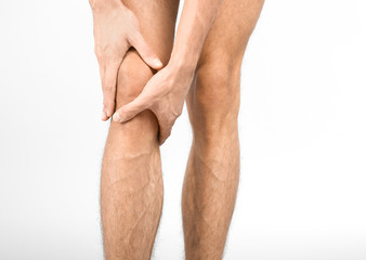 Young man suffering from knee pain on white background