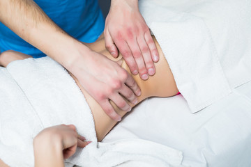 Masseur conducts anti-cellulite massage of the woman abdomen