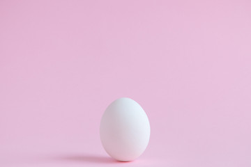 White egg isolated on pale rose background.