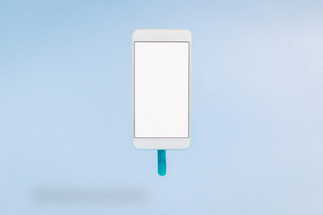 White smartphone with ice cream stick against blue background. Food and technology creative concept.