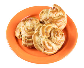 home eclairs on an orange plate isolated on a white background