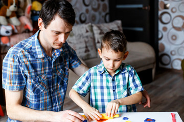 Fototapeta premium Picture of a father and a son playing with color play dough and cutters. Having fun with colorful modeling clay. Creative kids molding at home. Children play with plasticine or dough.