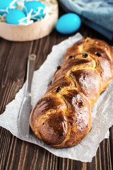 Homemade braided sweet bread with raisins on a wooden background