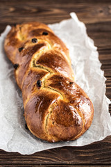 Homemade braided sweet bread with raisins on a wooden background