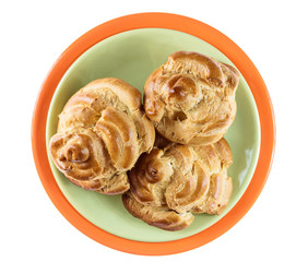 home eclairs on an orange plate isolated on a white background