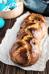 Homemade braided sweet bread with raisins on a wooden background