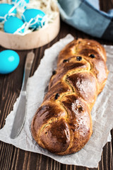 Homemade braided sweet bread with raisins on a wooden background