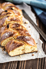 Homemade braided sweet bread with raisins on a wooden background