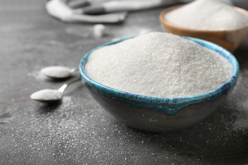 Bowl with pure sugar on grey background