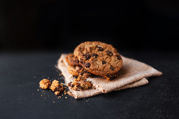 Chocolate cookies on linen napkin on black background. 