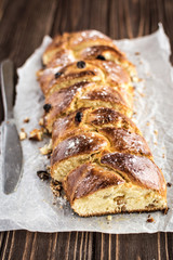 Homemade braided sweet bread with raisins on a wooden background