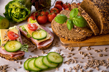 bread, fresh cereal bread with ham and vegetables, tasty healthy breakfast, top view, laid on the table