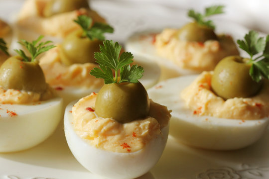 Spicy deviled eggs garnished with green olives and parsley