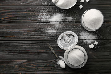 Jar, bowls and spoon with pure sugar on wooden background