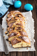 Homemade braided sweet bread with raisins on a wooden background
