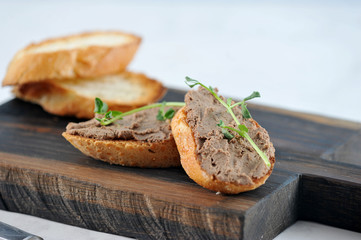 Slices of baguette with pate on a wooden board. Close-up. Macro shooting.
