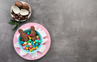 Composition with chocolate Easter bunnies and candies on gray background
