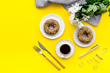 woman desk with flowers, coffee and donuts for breakfast in spring desing yellow background flat lay mock-up