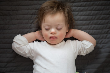 Fototapeta premium Cute baby boy with Down syndrome sleeping on the bed in home bedroom