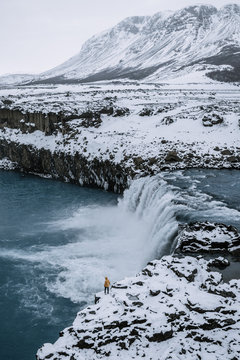 Scenic view of waterfall with snow covered mountain in background